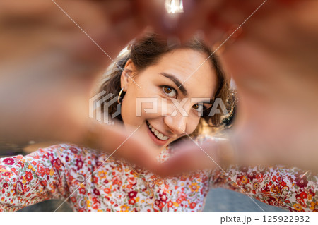 Young woman makes symbol of love, showing heart sign to camera, express romantic positive feelings 125922932