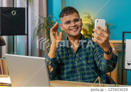 Happy Indian man taking selfie on smartphone communicating video call home online with subscribers Happy Indian man taking selfie on smartphone communicating video call home online with subscribers 125923029