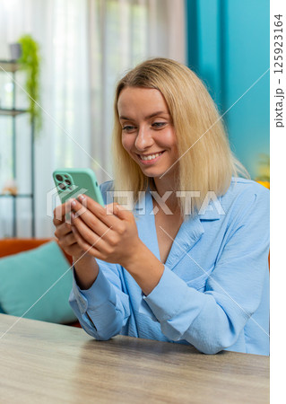 Young businesswoman working smartphone online remote distance job education sitting at home table 125923164