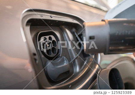 Close up of EV car plug in charge socket. All electric cars need to be charged by plugging in. You can recharge using a standard wall socket or an EV charging station. Close up of EV car plug in charge socket. All electric cars need to be charged by plugging in. You can recharge using a standard wall socket or an EV charging station. 125923389