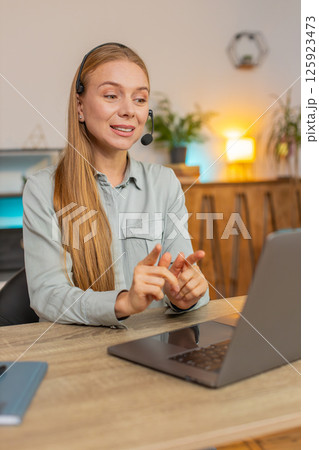 Mature female customer service representative with headset using laptop computer at home office desk Mature female customer service representative with headset using laptop computer at home office desk 125923473