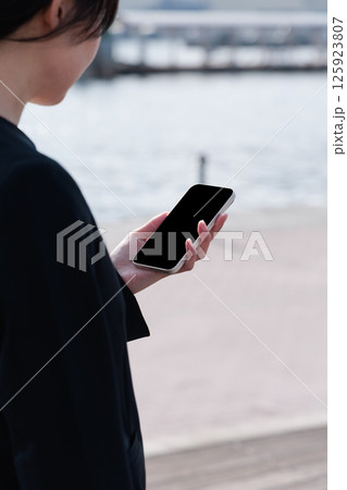 屋外でスマートフォンを操作するスーツの若い女性 屋外でスマートフォンを操作するスーツの若い女性 125923807