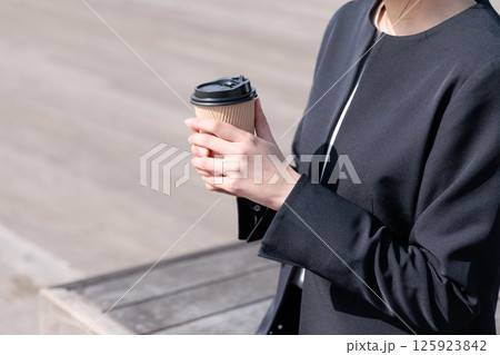 屋外でコーヒーを飲むスーツの若い女性 125923842