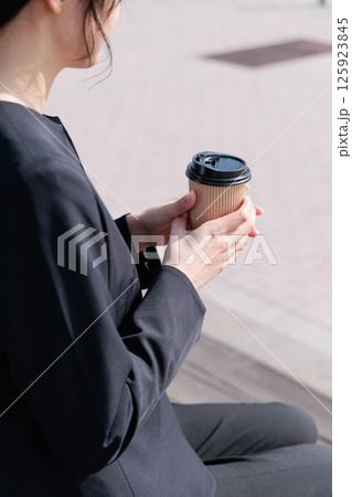 屋外でコーヒーを飲むスーツの若い女性 125923845