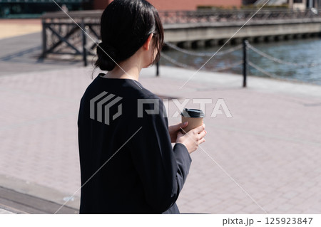 屋外でコーヒーを飲むスーツの若い女性 屋外でコーヒーを飲むスーツの若い女性 125923847