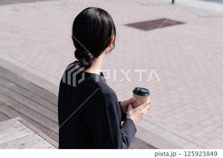 屋外でコーヒーを飲むスーツの若い女性 125923849