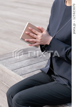 メモ帳を閉じるスーツの若い女性 125923870