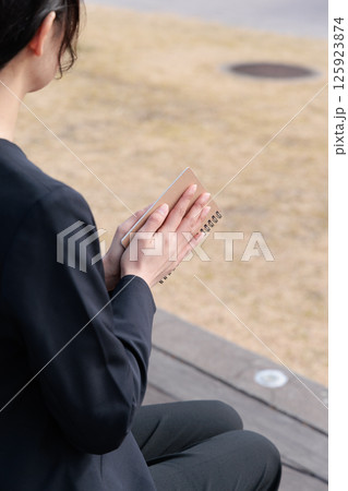 メモ帳を閉じるスーツの若い女性 125923874