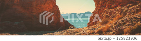 Rocky seascape on a sunny day. Seascape in daylight. View of the sea between two rocks. Horizontal banner 125923936