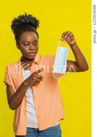 African American woman holding medical mask, gesturing explanation, focused expression, health topic African American woman holding medical mask, gesturing explanation, focused expression, health topic 125924006