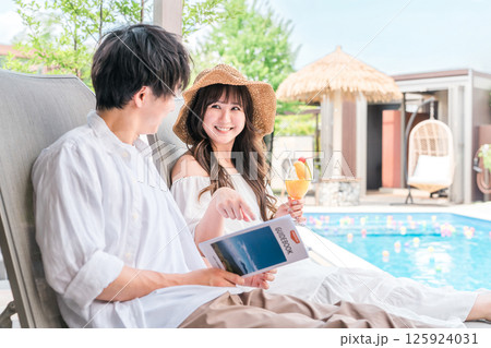 旅行でリゾートホテルのプールサイドのチェアに座るカップル・夫婦 125924031