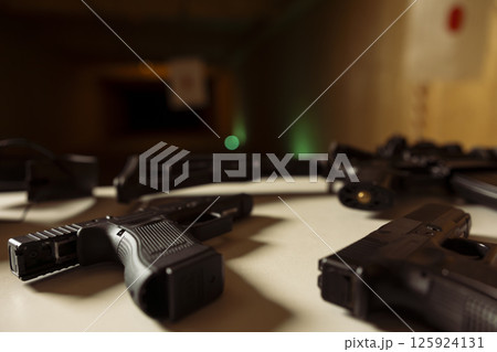 Practice weapons in military training outpost to be used by soldiers learning how to shoot firearms, preparing for combat. Close up shot of pistols and other guns in army shooting range Practice weapons in military training outpost to be used by soldiers learning how to shoot firearms, preparing for combat. Close up shot of pistols and other guns in army shooting range 125924131