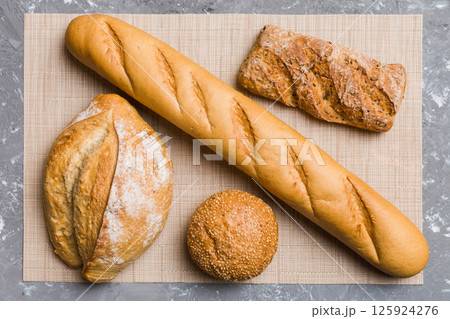 Assortment of freshly baked bread with napkin on rustic table top view. Healthy unleavened bread. French bread Assortment of freshly baked bread with napkin on rustic table top view. Healthy unleavened bread. French bread 125924276