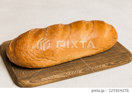 Freshly baked bread on cutting board against white wooden background. perspective view bread with copy space Freshly baked bread on cutting board against white wooden background. perspective view bread with copy space 125924278