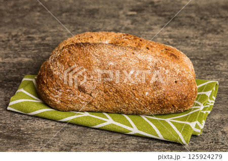 freshly baked bread with napkin on rustic table top view. Healthy white bread loaf isolated 125924279