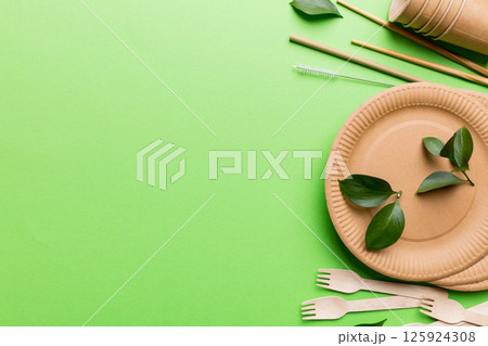 set of empty reusable disposable eco-friendly plates, cups, utensils on light white colored table background. top view. Biodegradable craft dishes. Recycling concept. Close-up 125924308