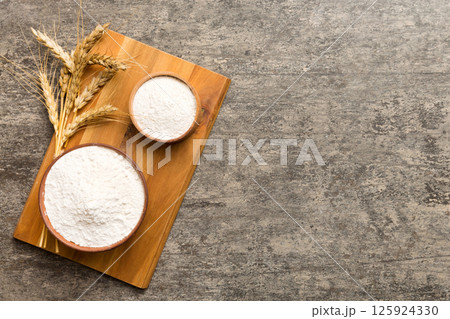 Flat lay of Wheat flour in wooden bowl with wheat spikelets on colored background. world wheat crisis 125924330