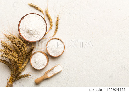 Flat lay of Wheat flour in wooden bowl with wheat spikelets on colored background. world wheat crisis 125924331