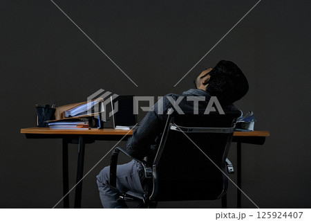 大量の書類に囲まれてオフィスチェアで眠り込む疲れ果てた男性の姿が物語る現実 大量の書類に囲まれてオフィスチェアで眠り込む疲れ果てた男性の姿が物語る現実 125924407