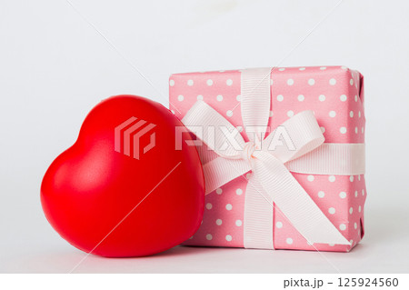 gift box with red bow and red heart on colored background. Perspective view. Flat lay gift box with red bow and red heart on colored background. Perspective view. Flat lay 125924560