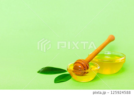 Honey in jar with leaves and honey dipper on colored background top view with copy text Honey in jar with leaves and honey dipper on colored background top view with copy text 125924588