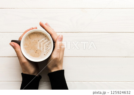 Minimalistic style woman hand holding a cup of coffee on Colored background. Flat lay, top view cappuccino cup. Empty place for text, copy space. Coffee addiction. Top view, flat lay 125924632