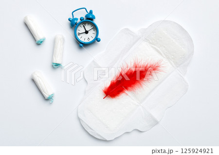 Ringing alarm clock with sanitary female tampons and menstrual sanitary pads. Medical concept of woman critical days and menstruation. Female daily hygiene. Copy space 125924921