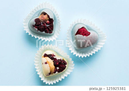 chocolate sweets in the form of a heart with fruits and nuts on a colored background. top view with space for text, holiday concept chocolate sweets in the form of a heart with fruits and nuts on a colored background. top view with space for text, holiday concept 125925381