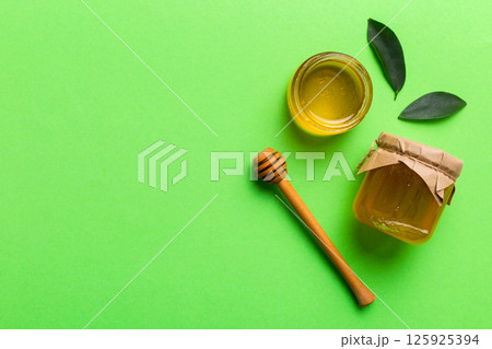Honey jar with wooden honey dipper on white background top view with copy space. Delicious honey bottle Honey jar with wooden honey dipper on white background top view with copy space. Delicious honey bottle 125925394