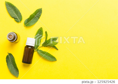 Natural Mint Essential Oil in a Glass Bottle. organic cosmetics with herbal extracts of mint on colored background Natural Mint Essential Oil in a Glass Bottle. organic cosmetics with herbal extracts of mint on colored background 125925426