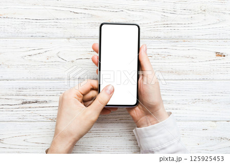 Top view of woman hands holding smart phone with blank copy space screen for your text message or information content. woman hand using phone white screen on top view Top view of woman hands holding smart phone with blank copy space screen for your text message or information content. woman hand using phone white screen on top view 125925453