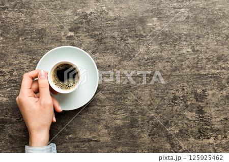 Minimalistic style woman hand holding a cup of coffee on Colored background. Flat lay, top view cappuccino cup. Empty place for text, copy space. Coffee addiction. Top view, flat lay Minimalistic style woman hand holding a cup of coffee on Colored background. Flat lay, top view cappuccino cup. Empty place for text, copy space. Coffee addiction. Top view, flat lay 125925462