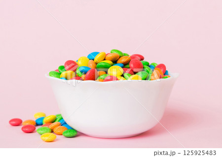 Multicolored candies in a bowl on a colored background. birthday and holiday concept. Top view with copy space 125925483