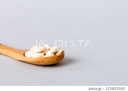 Heap of white pills on colored background. Tablets scattered on a table. Pile of red soft gelatin capsule. Vitamins and dietary supplements concept Heap of white pills on colored background. Tablets scattered on a table. Pile of red soft gelatin capsule. Vitamins and dietary supplements concept 125925503
