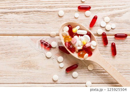 Vitamin capsules in a spoon on a colored background. Pills served as a healthy meal. Red soft gel vitamin supplement capsules on spoon Vitamin capsules in a spoon on a colored background. Pills served as a healthy meal. Red soft gel vitamin supplement capsules on spoon 125925504