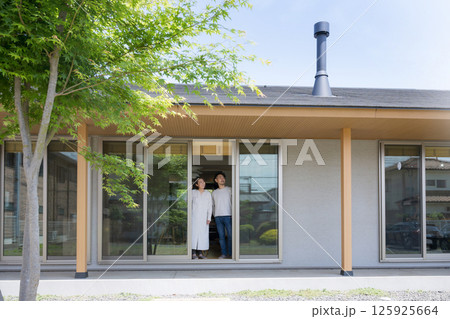 緑や暖炉の煙突のある平屋の縁側や縁の下で空を見上げる、眺める夫婦　 125925664