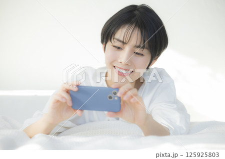 ベッドでくつろぐ女性　  125925803