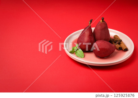 Pears in wine on plate on red background, space for text Pears in wine on plate on red background, space for text 125925876