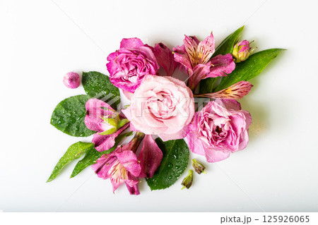 Beautiful bouquet featuring vibrant pink and purple flowers with water droplets, surrounded by lush green leaves 125926065