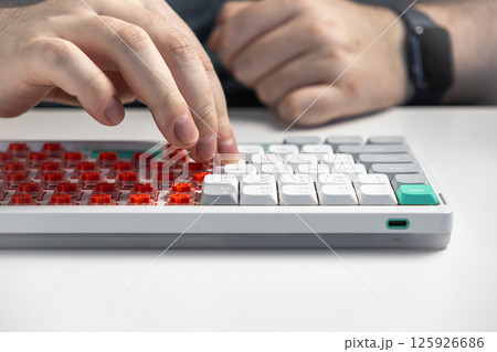 Hands placing keycaps onto low-profile mechanical keyboard switches for assembly 125926686