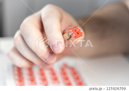 Hand holding red mechanical keyboard switch with tweezers during custom assembly process Hand holding red mechanical keyboard switch with tweezers during custom assembly process 125926709