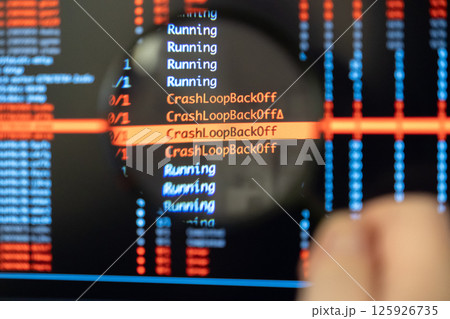 Man's hand holds magnifying glass over screen displaying highlighted CrashLoopBackOff error messages, symbolizing critical debugging work 125926735