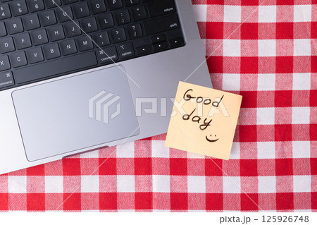 Laptop and inspirational Good day note on a casual red and white checkered table 125926748