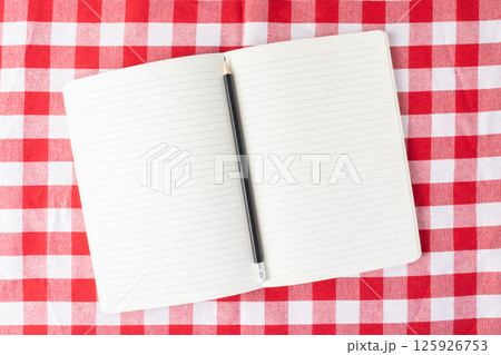 Open blank notebook with pencil on checkered tablecloth ready for writing recipes notes or ideas 125926753