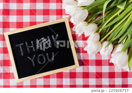 Blackboard with Thank You text and white tulips on tablecloth for gratitude message Blackboard with Thank You text and white tulips on tablecloth for gratitude message 125926757