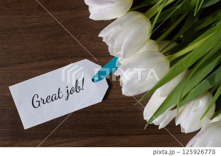 Tag with Great job message attached to fresh white tulips on wooden background ideal for celebrating achievement recognition and positive encouragement or reward Tag with Great job message attached to fresh white tulips on wooden background ideal for celebrating achievement recognition and positive encouragement or reward 125926778