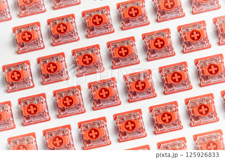 Top-down macro view of red hot-swappable mechanical switches installed on a white keyboard plate 125926833
