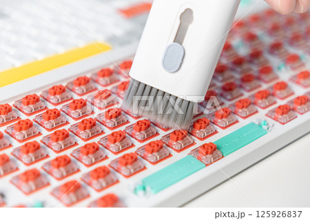 Vacuum brush cleaning red mechanical switches on colorful keyboard during custom PC build Vacuum brush cleaning red mechanical switches on colorful keyboard during custom PC build 125926837