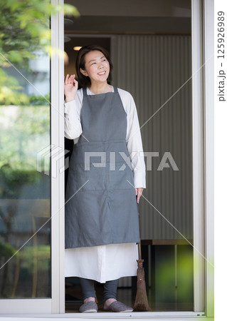 窓から外を眺める主婦のようなエプロンを付けた女性　ライフスタイルやセカンドライフ 125926989
