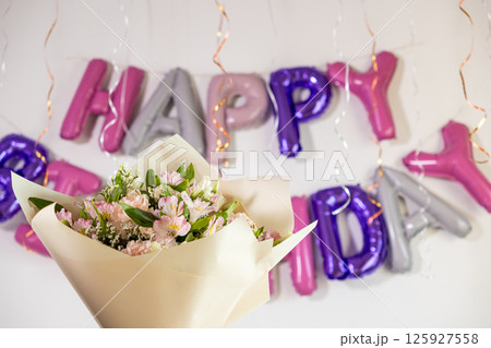 stunning bouquet of fresh flowers wrapped in elegant paper with vibrant happy birthday balloons and festive decorations in the background 125927558